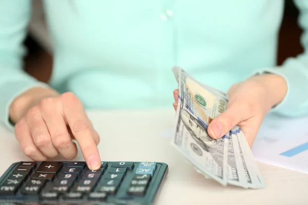 Жінка рахує гроші і працює на калькуляторі за столом — стокове фото