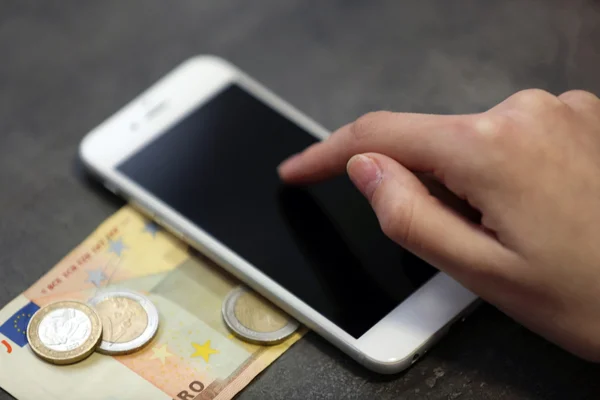 Mano con teléfono inteligente, billetes en euros y monedas sobre fondo gris. Gastos telefónicos —  Fotos de Stock