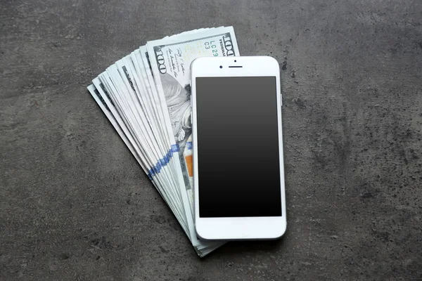 Smart phone con banconote in dollari su sfondo grigio. Fare soldi online — Foto Stock