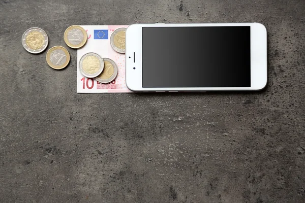 Smartphone con banconote e monete in euro su sfondo grigio. Spese telefoniche — Foto Stock