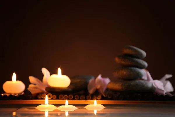 Balneario bodegón con piedras, velas y flores en el agua sobre fondo oscuro —  Fotos de Stock