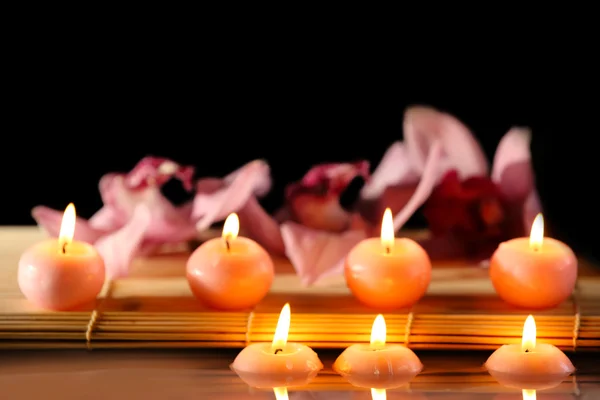 Spa ainda vida com pedras, velas e flores na água no fundo preto — Fotografia de Stock