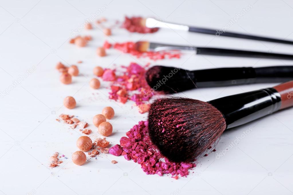 Makeup tools with powder on white background, close up