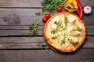 Lezzetli pizza ahşap arka plan üzerinde sebze ve otlar ile dekore edilmiş, yakın çekim