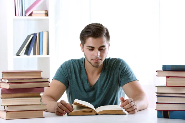 Junger Mann liest Buch am Tisch — Stockfoto