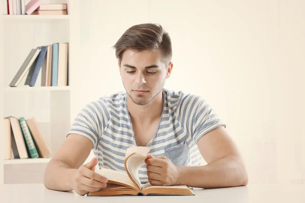 Jeune homme lisant un livre à table — Photo