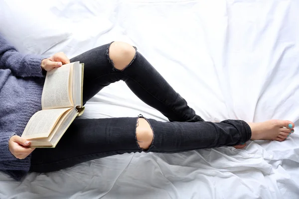 Žena v džíny na posteli — Stock fotografie