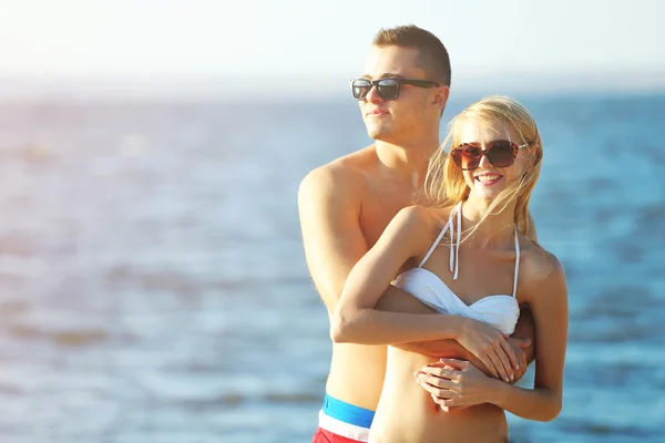 Lyckliga par kramas på stranden — Stockfoto