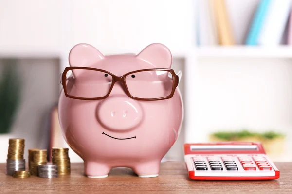 Свинка в очках с калькулятором и монетами — стоковое фото