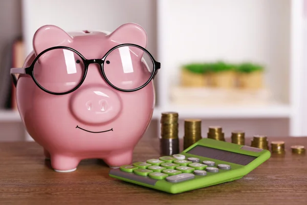 Sparschwein in Brille mit Taschenrechner und Münzen — Stockfoto