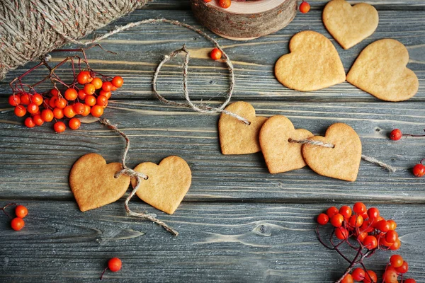 Heart shaped biscuits with ash berries and thread on wooden background, top view — Stock Photo, Image