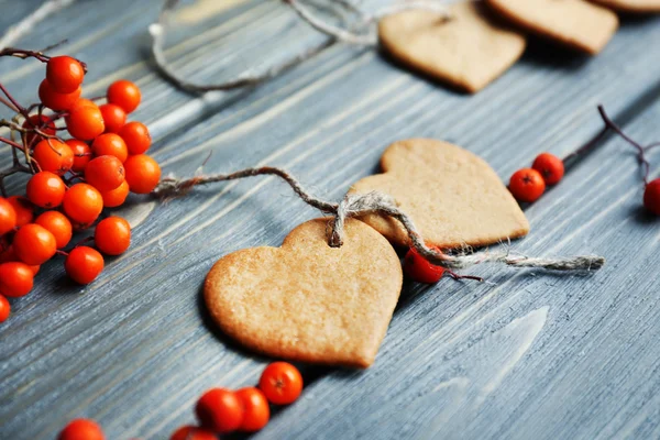 Sušenky s popelem bobule a vlákno na dřevěné pozadí ve tvaru srdce — Stock fotografie