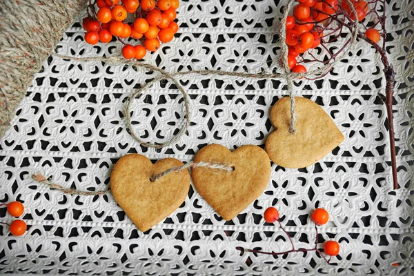 Heart shaped biscuits with ash berries and thread on a white tray — Stock Photo, Image