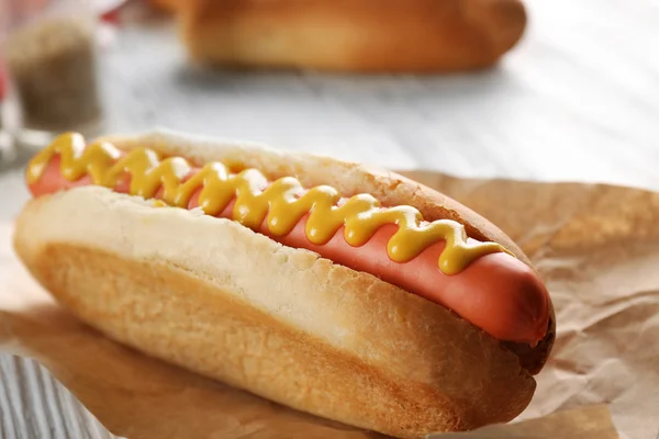 Hot dog on craft paper on wooden background, closeup — Stock Photo, Image