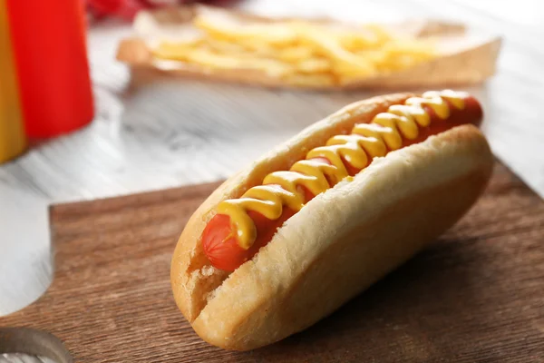 Hot dog with fried potatoes on craft paper — Stock Photo, Image