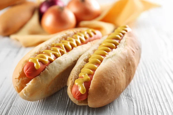 Hot-dogy a čerstvé cibule na dřevěné pozadí — Stock fotografie