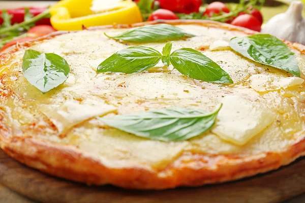 Gustosa pizza decorata con basilico e verdure su fondo ligneo, primo piano — Foto Stock