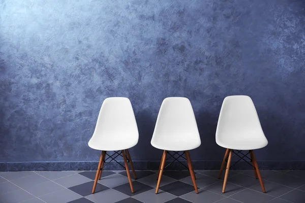 Witte stoelen op een grijze muur — Stockfoto