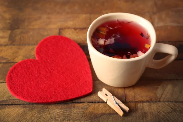 Xícara de chá de frutas com coração vermelho e closeup closeup pano de fundo de madeira — Fotografia de Stock