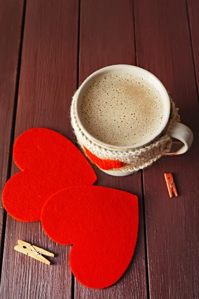 Taza de café con leche, pinzas de ropa y dos corazones sobre fondo de madera —  Fotos de Stock