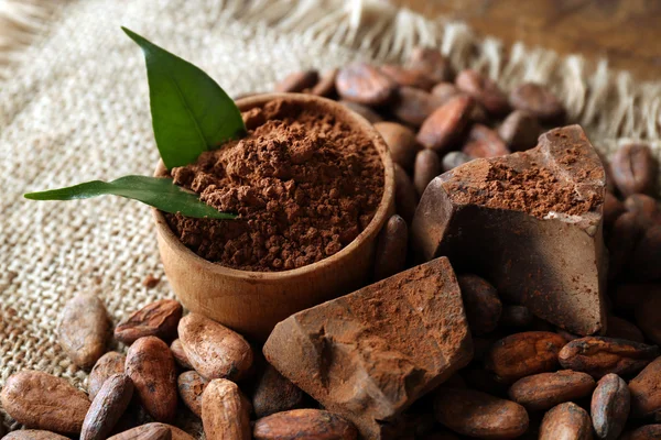 Bowl with aromatic cocoa powder and green leaf on a sacking, close up — Stock Photo, Image