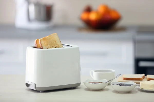 Toaster with dishes on a light kitchen table — Stock Photo, Image