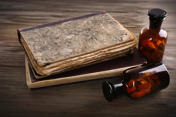 Libri e pillole sul tavolo di legno — Foto Stock