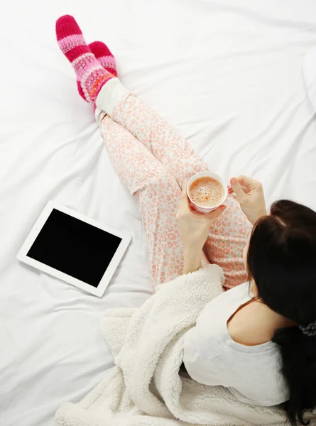 Woman in pajamas with tablet drinking coffee — Stock Photo, Image