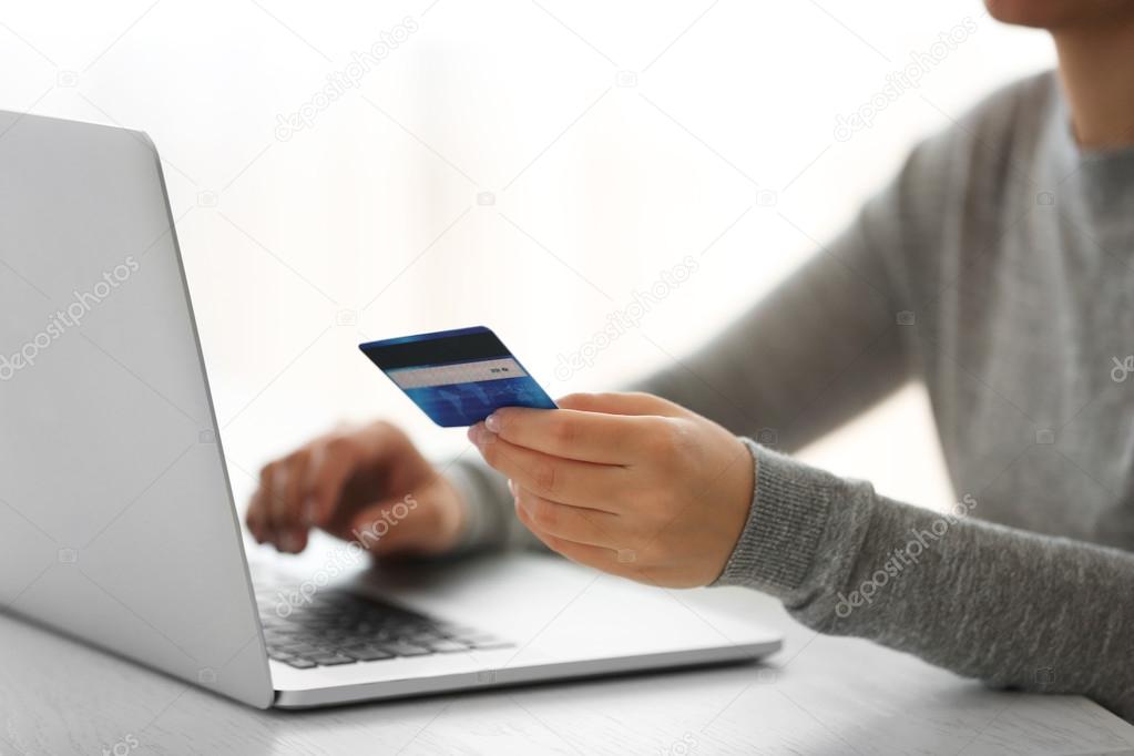 E-commerce concept. Woman with credit card and laptop, close up