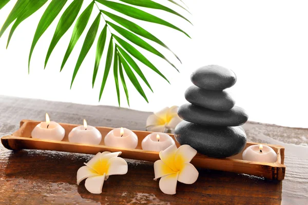 Pietre termali con candele, plumeria e bambù, isolate su bianco — Foto Stock