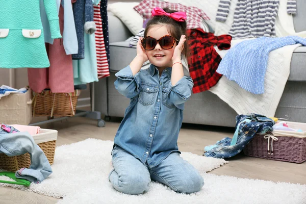 Маленькая девочка в комнате с большим количеством одежды — стоковое фото