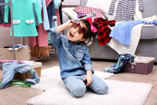 Klein meisje in de kamer met een heleboel kleding — Stockfoto