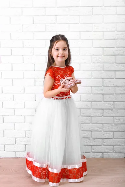 Petite fille en robe sur un fond de mur de briques blanches — Photo