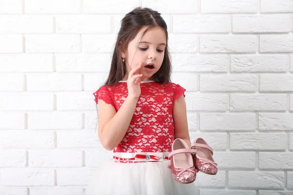 Kleines Mädchen im Kleid auf weißem Backstein-Hintergrund — Stockfoto