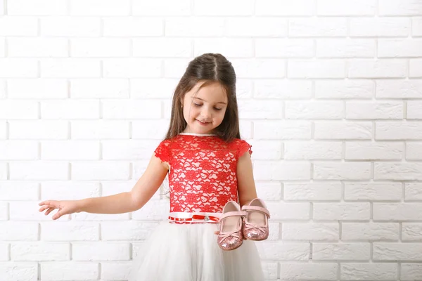 Petite fille en robe sur un fond de mur de briques blanches — Photo