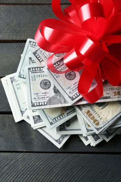 Montón de dólares con arco como regalo — Foto de Stock