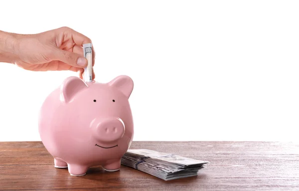 Hombre poniendo billete en caja de dinero de cerdo —  Fotos de Stock