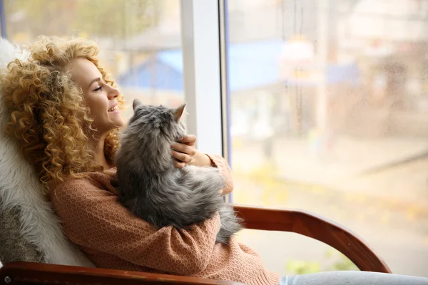 Ung kvinna och katt bredvid fönstret — Stockfoto