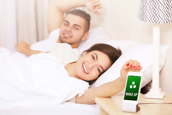 Пара прокидається з мобільним будильником — стокове фото