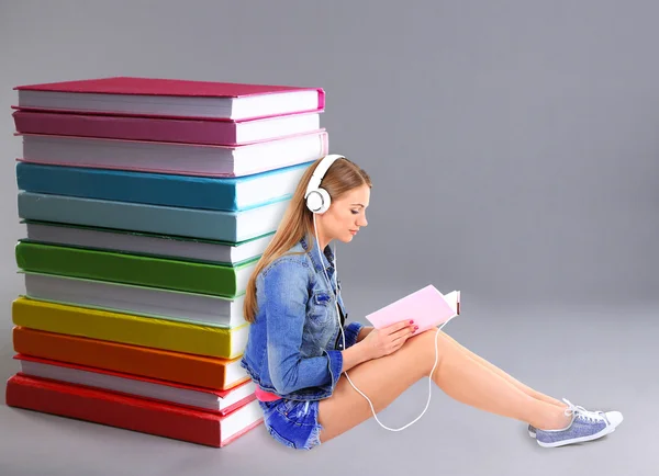 Жінка з навушниками біля стопки книг — стокове фото