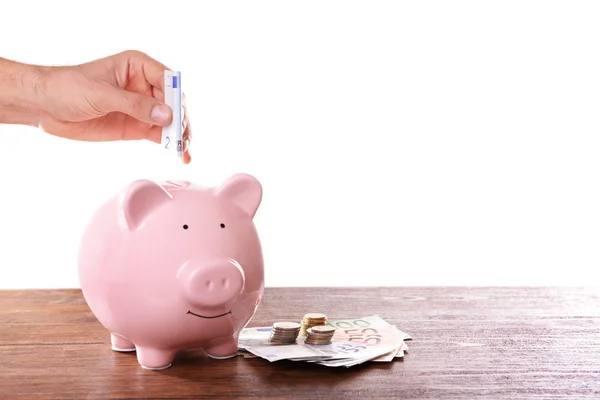 Man putting banknote in pig moneybox — Stock Photo, Image