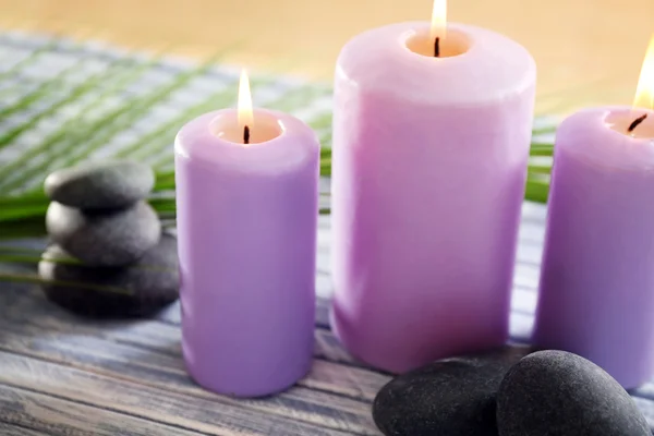 Velas púrpuras con piedras de spa — Foto de Stock