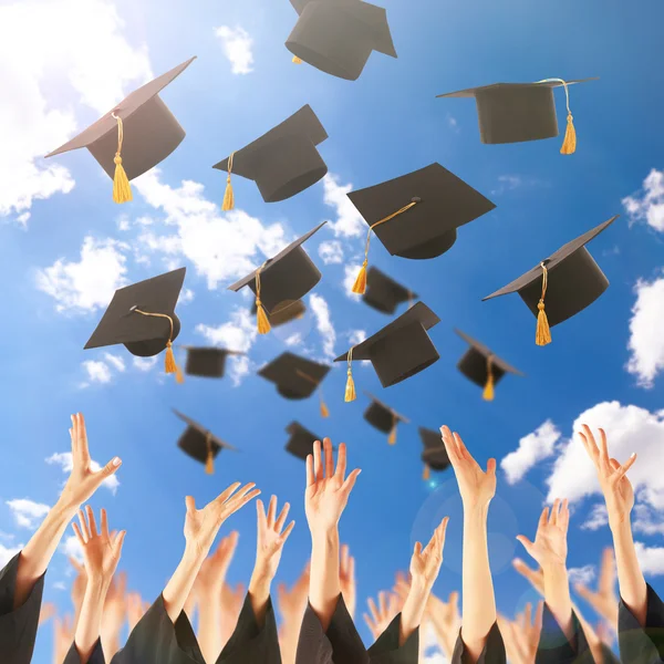 Graduados manos lanzando sombreros de graduación — Foto de Stock