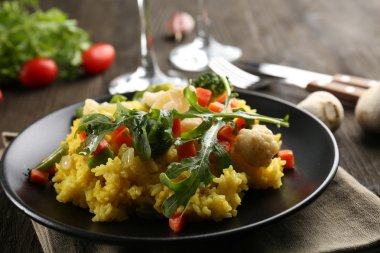 Hizmet ahşap masa üzerinde sebze risotto ile siyah plaka