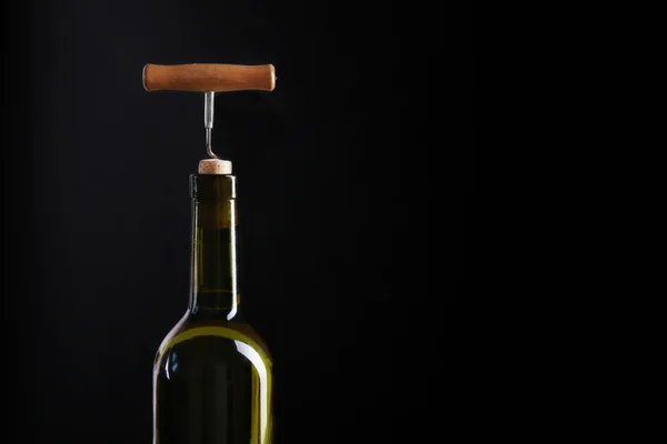 Corkscrew e garrafa de vinho em um fundo preto — Fotografia de Stock