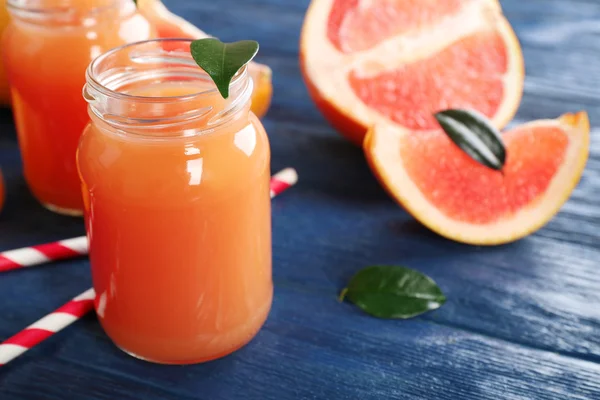 Grapefruit-lé, az üveg és a friss gyümölcsök, sötét kék fa háttér — Stock Fotó