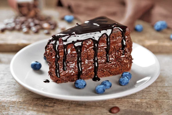 Csokoládé torta csokoládé krém és friss áfonya, a lemez, a fából készült háttér — Stock Fotó