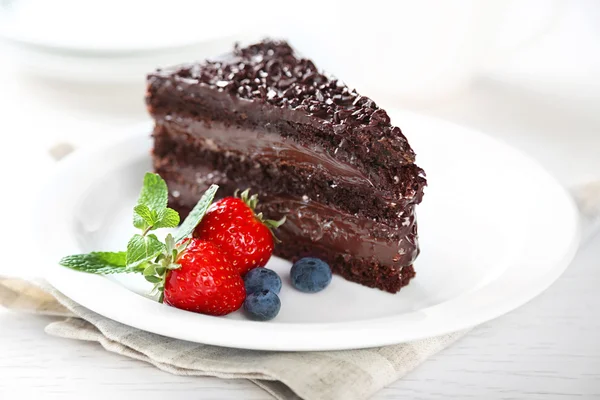 Schokoladenkuchen mit Schokoladencreme und frischen Beeren auf Teller, auf hellem Hintergrund — Stockfoto