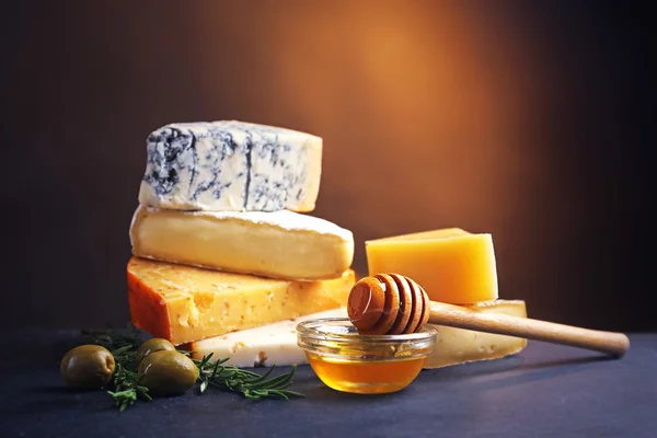 Different kinds of cheese, honey and olives on the table, close up — Stock Photo, Image