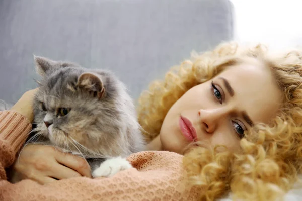 Mladá žena a kočka na pohovce — Stock fotografie